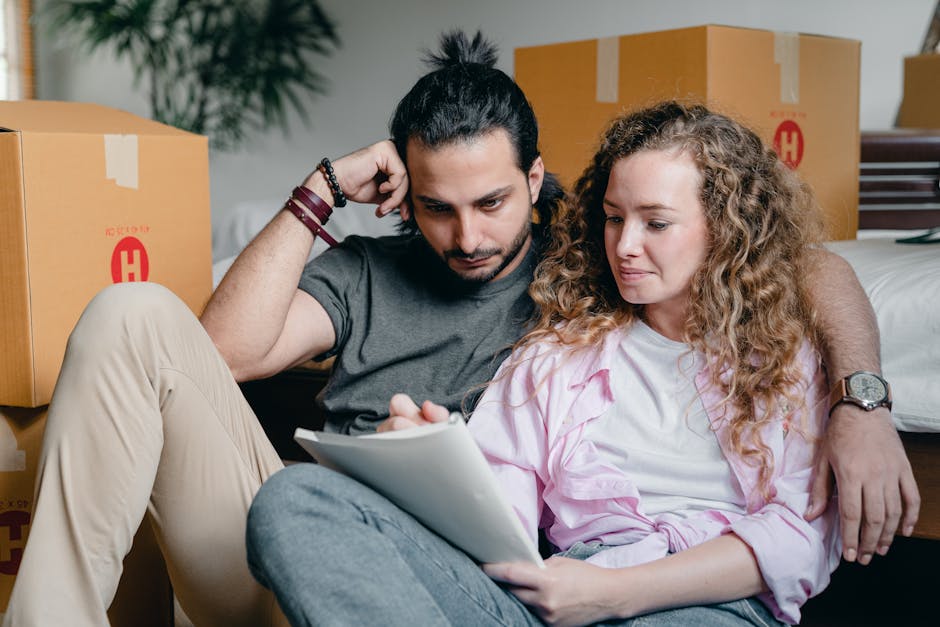 In a bright, well-lit room with wooden-framed windows and natural daylight, a woman and a young girl are engaged in home relocation activities. The woman, with dark hair tied back, is leaning over a l